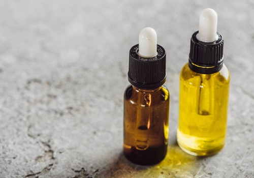 Two glass dropper bottles filled with golden skincare oil on a gray surface