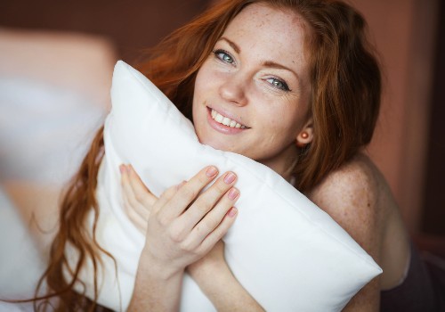 Smiling woman holding a white pillow against her cheek