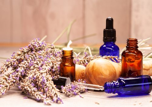 Amber and blue essential oil bottles arranged with lavender sprigs on a wooden surface