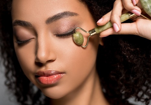 Woman with her eyes closed rolling a green jade facial roller along her cheekbone