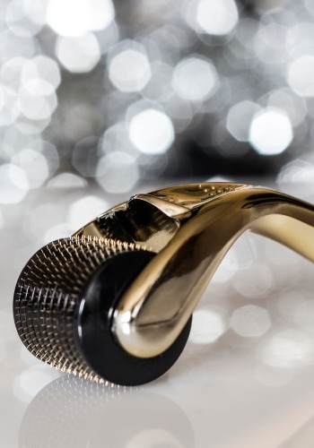 Close-up of the cylindrical needle head on a gold-handled derma roller