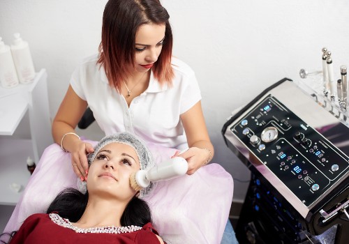 Practitioner using an electric facial cleansing device on a reclining client in a treatment room