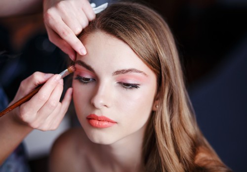 Makeup artist applying pink eye shadow to a woman's eyelid with a small brush