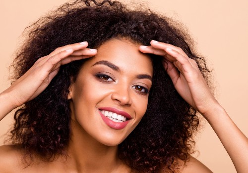 Smiling woman with curly hair holding both hands near her temples