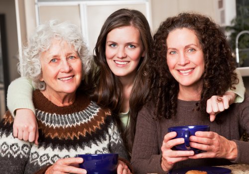 Three generations of women smiling together, with two holding blue mugs