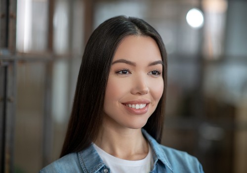 Smiling woman with long straight hair wearing a light blue jacket over a white top