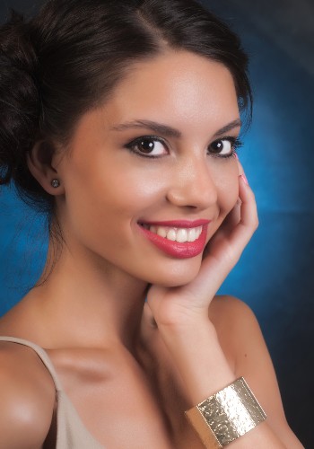 Smiling woman resting her hand against her neck, with a wide silver bracelet on her wrist