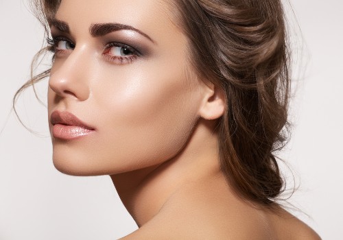 Close-up portrait showing a woman's luminous makeup finish and highlighted cheekbone