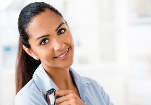 Smiling woman holding a pair of glasses near her chest