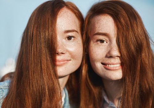 Two red-haired women with freckles smiling with their heads close together