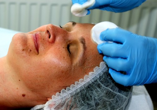 Practitioner using cotton pads on a reclining woman's face during a skincare treatment