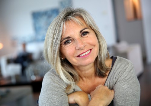 Smiling gray-haired woman leaning forward with one hand resting near her shoulder