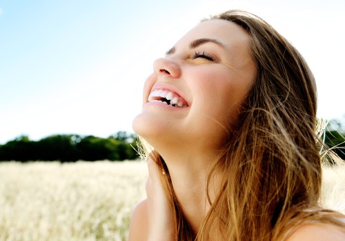 Woman smiling with her eyes closed and her face tilted upward in a sunny field