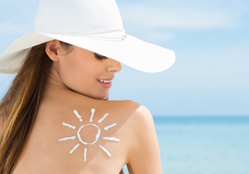 Woman in a white sunhat with sunscreen drawn in the shape of a sun on her shoulder