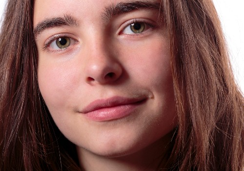 Close-up portrait of a woman with loose brown hair showing the natural texture of her cheeks