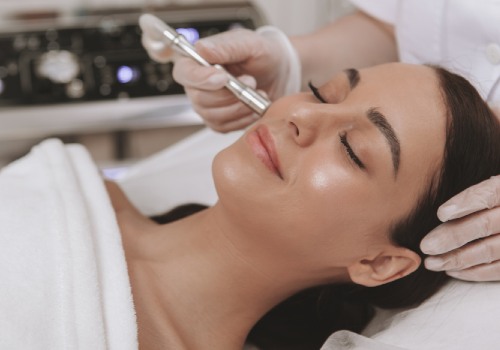 Gloved practitioner applying a microdermabrasion wand beside a reclining woman's nose