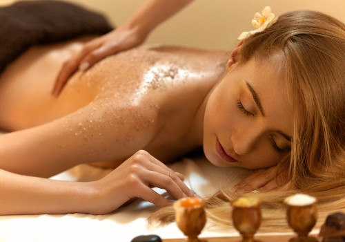 Woman receiving a body scrub and back massage while lying on a spa treatment table