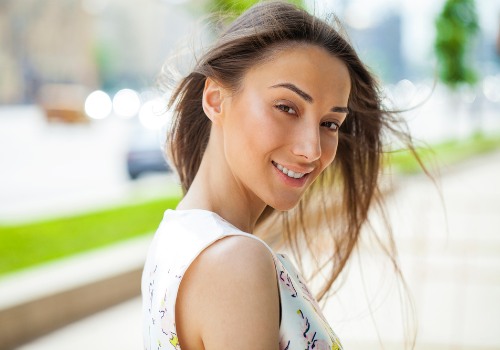 Smiling woman looking back over her shoulder outdoors beside a walkway
