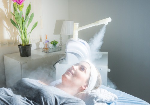 Woman reclining beneath a salon facial steamer that directs a plume of mist toward her face
