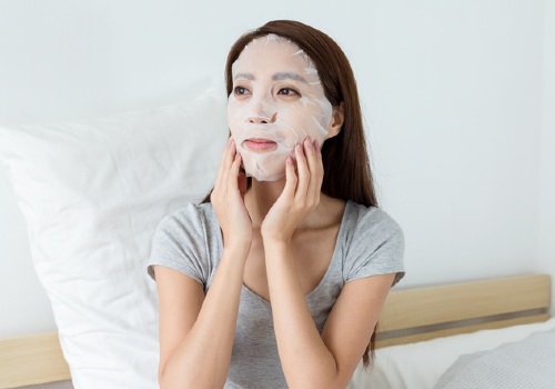 An Asian woman using a facial mask