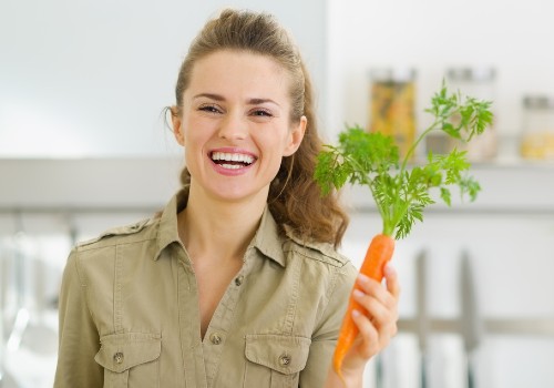 A smiling young housewife holding a carrot