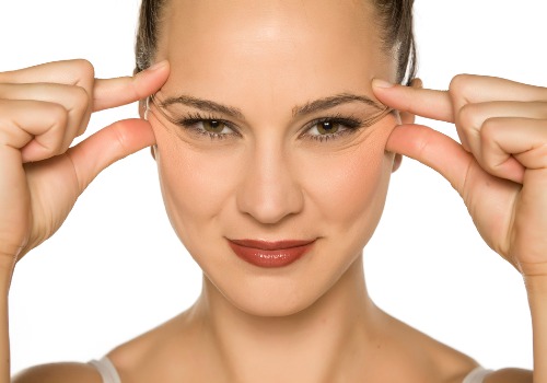 A young woman pinching her eye wrinkles with her fingers